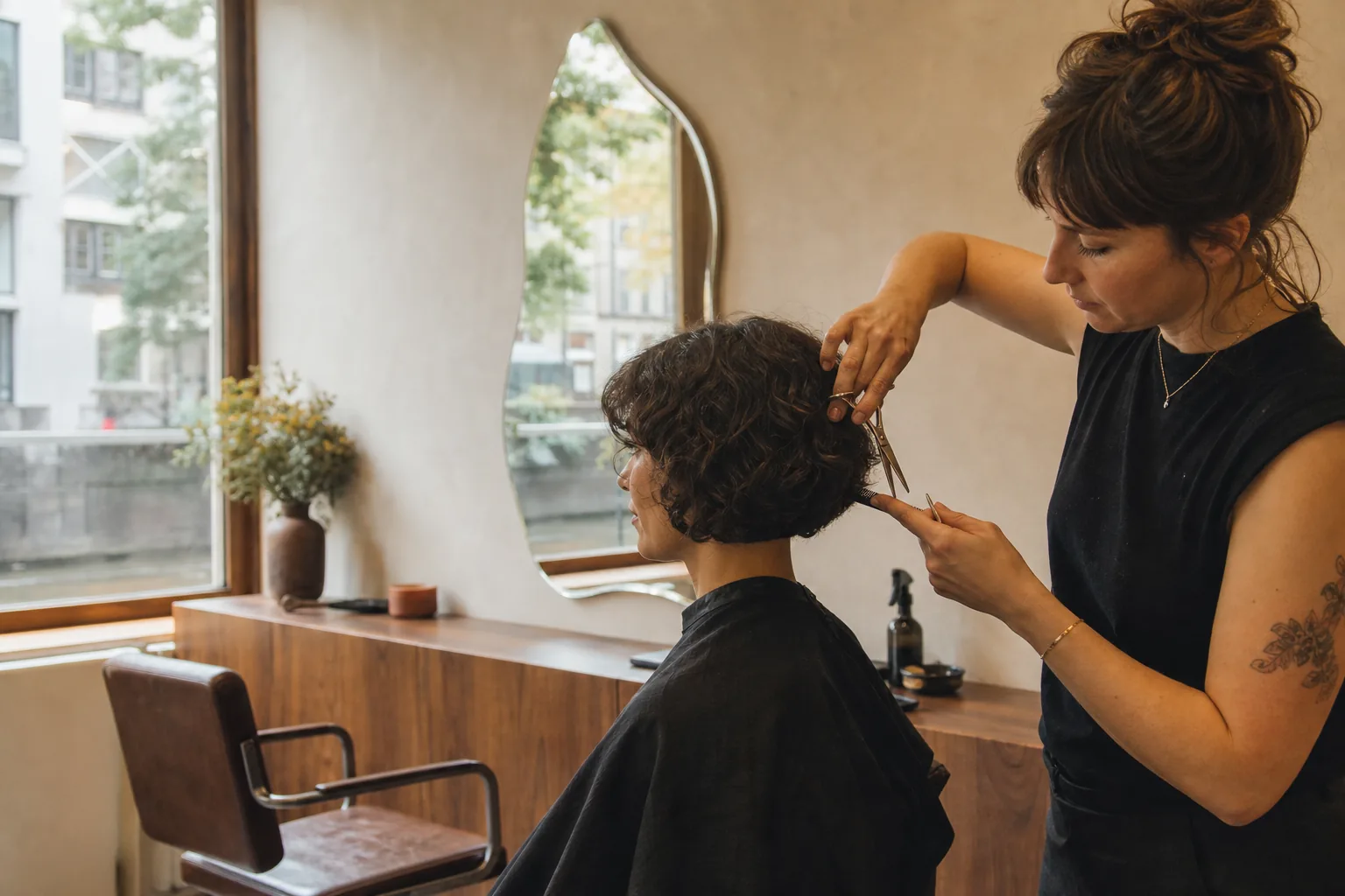 Kapper die zorgvuldig een boblijn knipt in een warme Amsterdamse salon